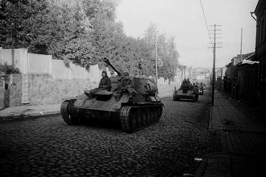 Колонна советских самоходок СУ-76 движется по улице городка...