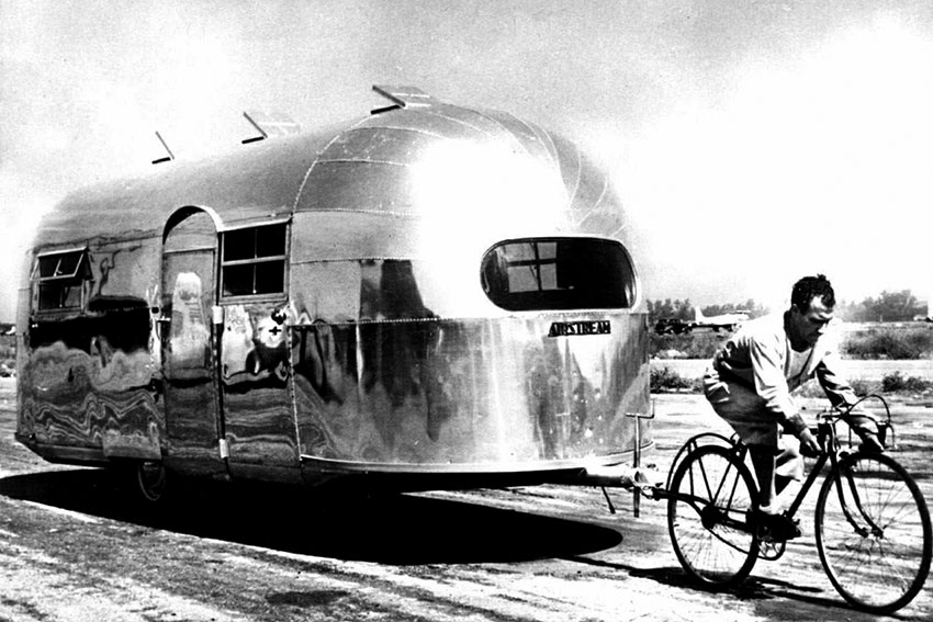 Велосипедист буксирует туристический прицеп Airstream на своем...